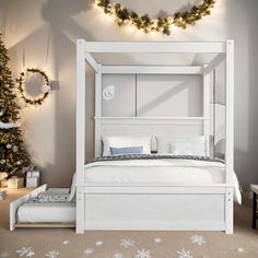 a white bed sitting in a bedroom next to a christmas tree with lights on it