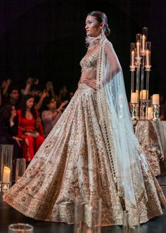 An ethereal lehenga set that celebrates the resplendence of exemplary handwork craftsmanship. The set has a lehenga, a blouse, a dupatta and a veil. A surreal lehenga tailored in luxurious raw silk with overall intricate embroidery of salli, pearls, diamonds, and beads that will catch light from every angle. Ornate with floral motifs, it brings to life the allure of botanical dreams. The sleeveless blouse is intricately stitched in a deep sweetheart neckline with all-over exquisite embroidery and a back hook closure. The heavy net dupatta displays stunning cut-work heavy with mesmerizing hanging pearl tassels that exudes a timeless appeal. Complete with a veil, this enchanting silhouette exhibits a regal flair and an unmatched level of elegance. Dry-clean only if required. Slight variation Elegant Lehenga With Sheer Dupatta For Festivals, Luxury Cream Raw Silk Lehenga, Embellished Chandbali Dupatta For Wedding, Wedding Choli With Sheer Dupatta For Festivals, Bollywood Style Wedding Lehenga With Sheer Dupatta, Embellished Lehenga For Wedding And Festivals, Wedding Lehenga Embellished For Festivals, Wedding Lehenga With Sheer Dupatta For Navratri, Wedding Gown With Sheer Dupatta For Navratri