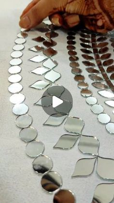 a person is making some decorative mirrors on the table with their hands and thumbnails