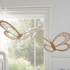 two butterfly shaped lights hanging from the ceiling in a child's room with white walls and windows