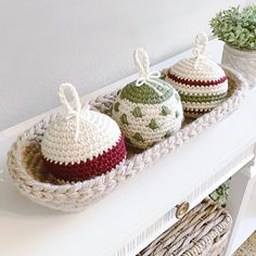 three crocheted ornaments sitting on top of a white table next to a potted plant