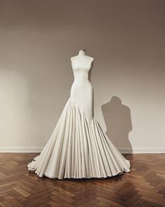 a dress on display in a room with wood flooring and white walls, behind which is a mannequin's head