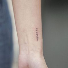 a small tattoo on the wrist that says breathe