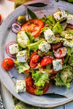 a salad with tomatoes, cucumbers, onions and feta cheese on it