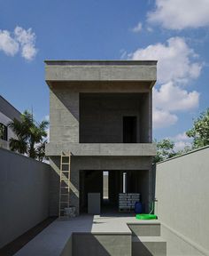 a concrete building with stairs leading up to the top floor and an open area in front of it