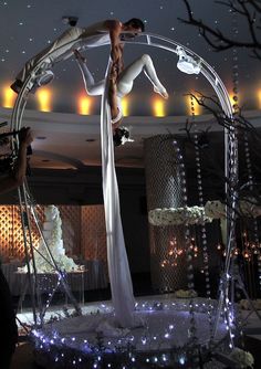 a woman standing on top of a pole in the middle of a room with lights