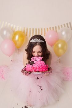 a woman wearing a tiara and holding a cake with pink frosting on it