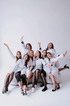 a group of women sitting next to each other on top of a white couch with their arms in the air