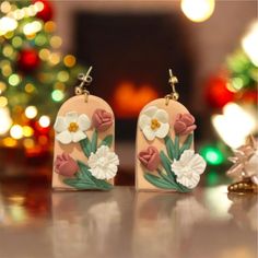 the earrings are decorated with flowers and green leaves on pink, white and red background