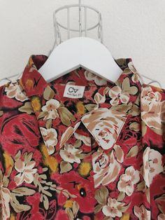 Vintage floral print polyester blouse from the 1980's. Women's button down floral print blouse in red, green, beige and yellow colors. Has elastic bottom hem and a pleated detail on the shoulders (with shoulder pads). Oversized fit. Material: 100% Polyester Size: 44 DE which is 14 US or XL. Model on the picture is 40 DE. To be sure this item would fit you, please look at the measurements below. Measurements (taken while blouse is lying flat, double waist): Shoulder to Shoulder (from seam to seam Red Retro Print Shirt For Spring, Red Collared Printed Blouse, Red Printed Collared Blouse, Red Floral Print Retro Shirt, Red Retro Floral Print Shirt, Retro Red Floral Print Shirt, Red Vintage Print Shirt, Red Vintage Shirt With Vintage Print, Vintage Red Shirt With Floral Print