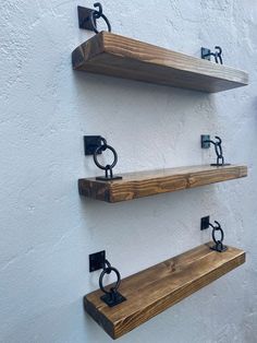 three wooden shelves mounted to the side of a white wall with metal brackets on them