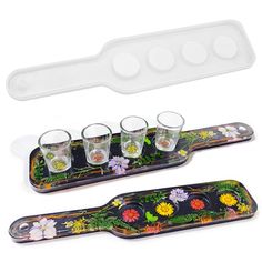 four shot glasses and tray with flower designs on the bottom, one filled with water