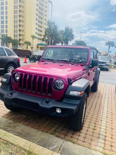 a pink jeep is parked on the side of the road