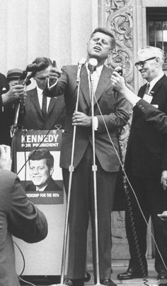 a black and white photo of a man speaking into a microphone