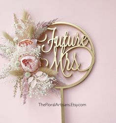 a cake topper that says future mrs on it with flowers and feathers in the middle