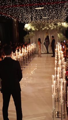 a man and woman are standing in front of rows of candles at a wedding ceremony