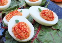 deviled eggs with red sauce on them sitting on top of lettuce leaves