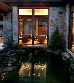 a house with a pond in front of it and glass doors leading to the outside