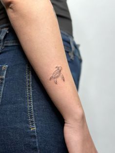 a small turtle tattoo on the left arm