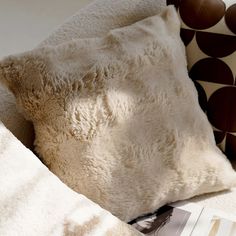 a white pillow sitting on top of a bed next to a brown and white blanket