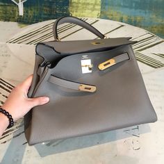 Description HRMS Kelly Grey Bag In Epsom With Gold Toned Hardware Bag For Women 7.5in/19cm Rep 1:1 Size: 19 x 5.5 x 12.5 cm / 7.5 x 4.5 x 2.2 inches (Length x Height x Width) Hermès Gold Sellier Kelly 19cm of epsom with gold hardware. This limited edition Kelly has white contrast stitching, a front toggle closure, a single rolled handle and an optional shoulder strap. The interior is lined with Gold chevre and has one open pocket on the back wall. 2.5″ handle drop Includes box, dust bag. This pr True Mirror, Louis Vuitton Shirt, Hermes Kelly 28, Chanel Shirt, Grey Bag, Togo Leather, Stylish Handbags, Gucci Gg Marmont, Birkin 25