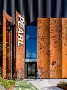 a man walking past an entrance to a building with large metal panels on the side