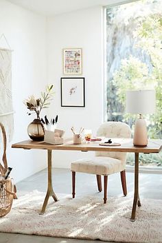 a table with two chairs and a vase on top of it in front of a window