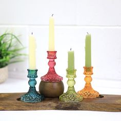 three candles are sitting next to each other on a wooden board with a potted plant in the background