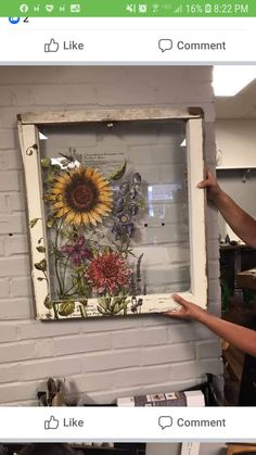 someone is holding up an old window with flowers on it and the frame has been painted white