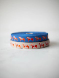 two rolls of washi tape with red and orange horses on them, sitting on a white surface