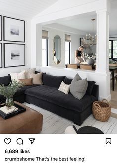 a living room with white walls and black couches, large mirror on the wall