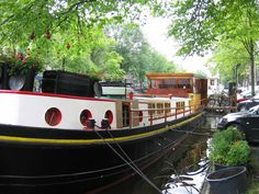 a black and white boat parked on the side of a river next to other boats