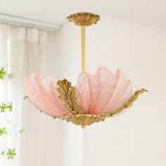 a pink and gold chandelier hanging from a ceiling in a room with white walls