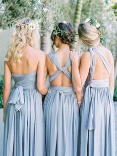 three bridesmaids in long gray dresses with flowers on their head and one wearing a flower crown