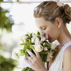 a woman holding a bouquet of flowers in her right hand and looking down at it