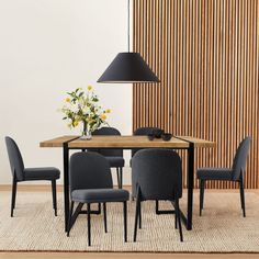 a dining room table with chairs and a lamp on the wall next to an area rug