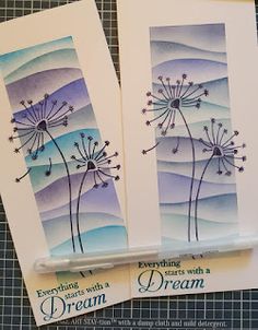 two cards with dandelions on them sitting next to each other in front of a piece of paper