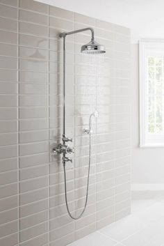 a shower head with thermostaer and handset in a white tiled bathroom