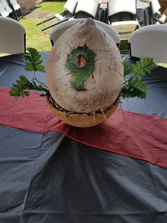 an odd looking object sitting on top of a blue table cloth with chairs in the background