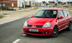 a red car is parked on the side of the road