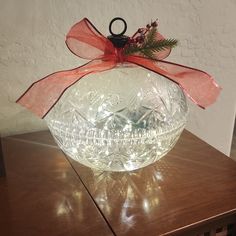 a clear glass bowl sitting on top of a wooden table with a red ribbon around it