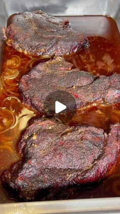 some meat is cooking in a pan with sauce on the top and bottom side,