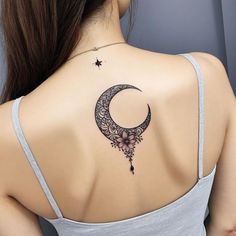 the back of a woman's shoulder with a crescent and flowers tattoo on it