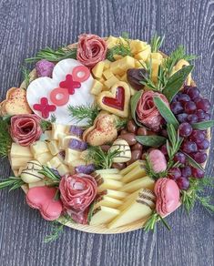 a bowl filled with lots of different types of cheese and fruit on top of a wooden table