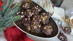 chocolate cookies are on a plate next to a cup of coffee and a christmas tree