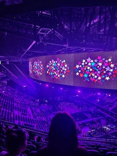 an arena filled with lots of people sitting in chairs and looking at the stage that has stars on it