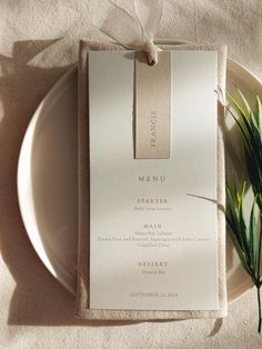 a table setting with an empty menu card and some flowers on the plate, next to it