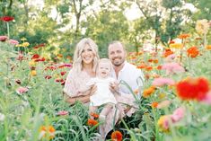 a man and woman holding a baby in a field of flowers