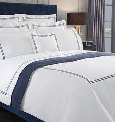 a bed with white sheets and blue trimmings