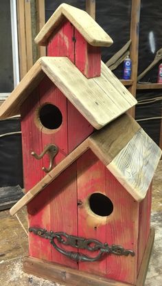 a red birdhouse with chains hanging from it's sides and the roof is made out of wood